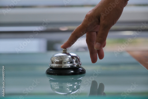 Close-up fore finger pressing a service bell on a reception desk photo