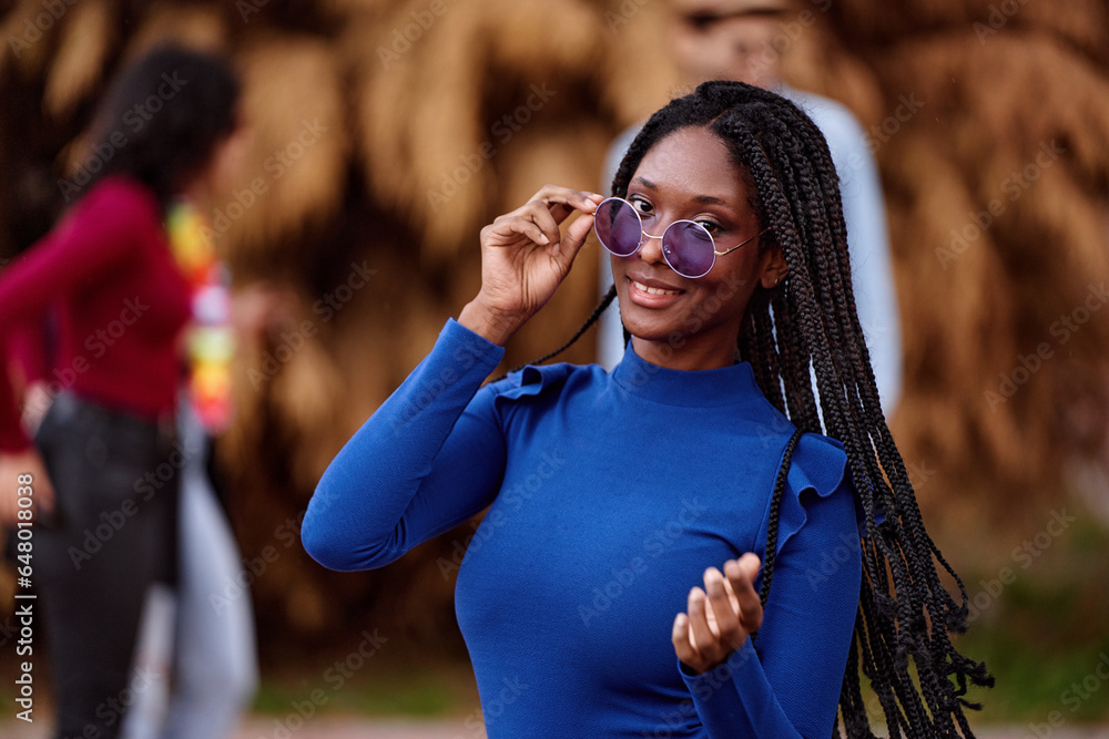 African American woman with sunglasses smiling while having fun at an outdoor party.