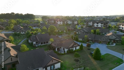Retirement housing in modern villas and condos. Aerial descending shot at sunset in American suburbia. 55+ community at retirement home.