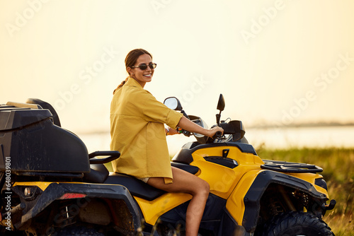 Portrait of a beautiful woman driving a rented quad bike through nature.