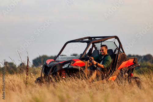 A happy man enjoying an adventure and driving a quad bike off-road.