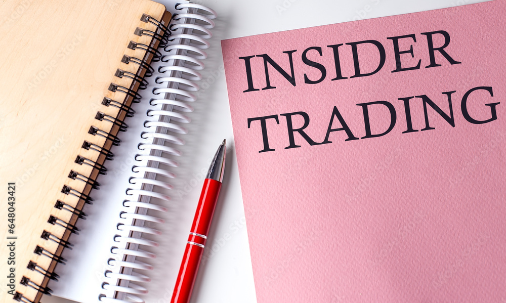 INSIDER TRADING word on the pink paper with office tools on white background INSIDER TRADING word on the pink paper with office tools on white background