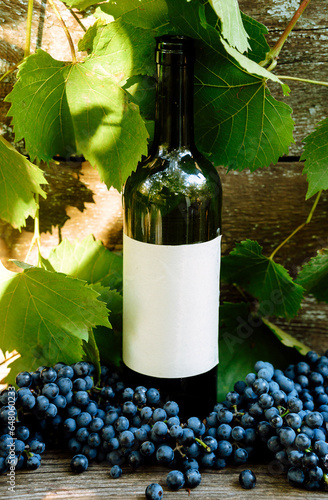 Green bottl of wine near with grapes and leaves. Bottle with clean label for your logo and text	 photo