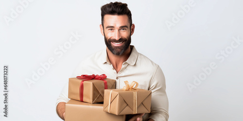 A dark-haired man with a beard holds gift boxes in his hands, smiling © Yuliya