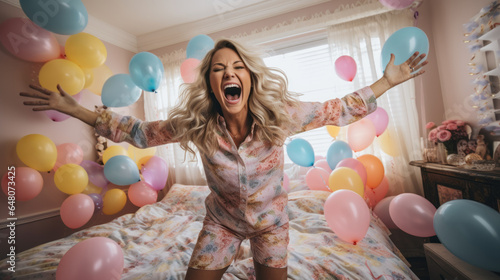 Happy woman dancing at home on her birthday in her pajamas, surrounded by a sea of colorful balloons, room is filled with laughter and the joy of party celebration photo