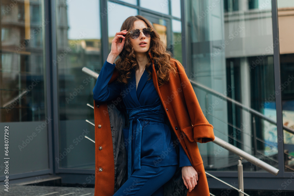 beautiful stylish woman walking in street stairs dressed in warm brown coat and blue suit