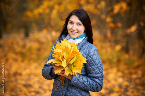Beautiful young woman with a bouquet of autumn leaves