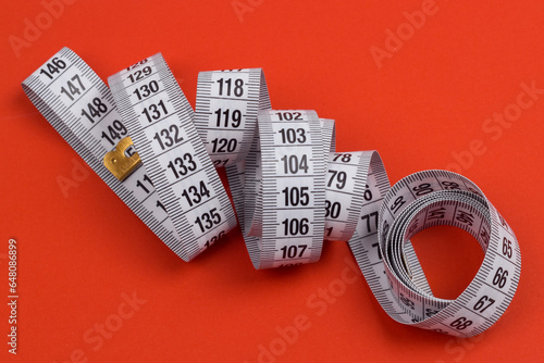 Centimeter tape, fitness and weight loss. Tailor's meter, for sewing, on a blue background. Meter, tape measure, to measure the body, waist in centimeters.