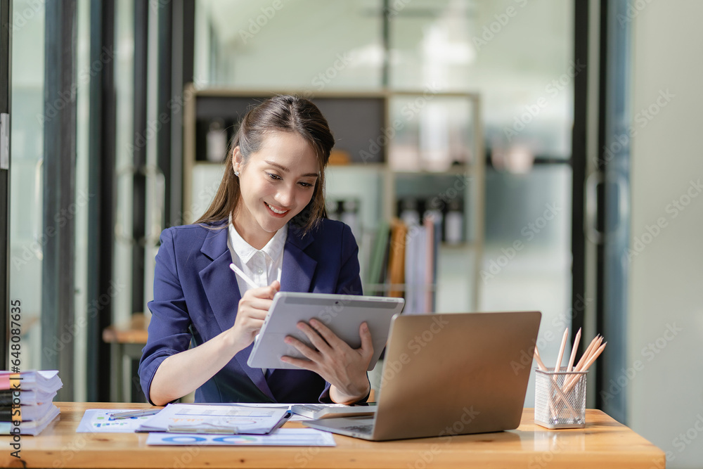 Asian businesswoman working with papers and laptop sitting at table in office, analyzing business accounting calculations and financial planning concepts. Asian businesswoman working with papers and laptop sitting at table in office, analyzing business accounting calculations and financial planning concepts.