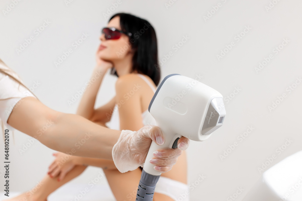A close-up shot of a laser hair removal device in front of a young client preparing for the procedure. Healthy and smooth body advertising concept. A close-up shot of a laser hair removal device in front of a young client preparing for the procedure. Healthy and smooth body advertising concept.
