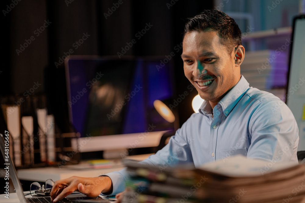 Asian man in dark office, company employee working overtime, working in the middle of the night, working overtime of a company employee who is busy and working hard. Overtime concept.