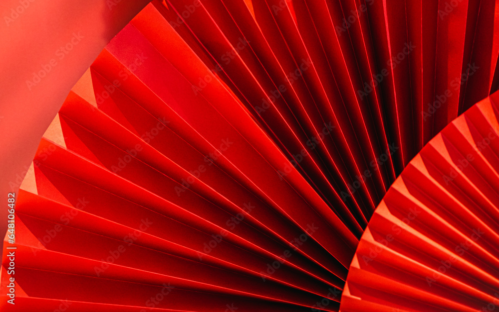 Background with vibrant bright red paper oriental craft fans. Dark texture banner with deep shadows. Chinese New Year celebration. Traditional decor for lunar calendar party.Festive decoration