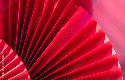 Background with vibrant bright red paper oriental craft fans. Dark texture banner with deep shadows. Chinese New Year celebration. Traditional decor for lunar calendar party.Festive decoration