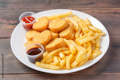 Nuggets sur une assiette avec des frites et sauces.  photo