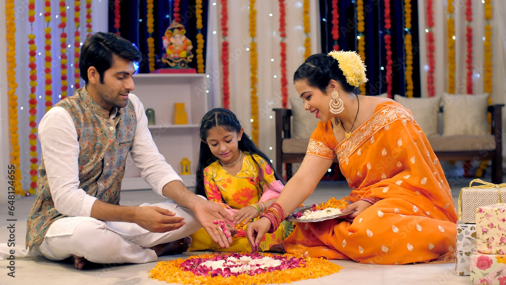 An Indian nuclear happy family makes rangoli with flowers and petals ...