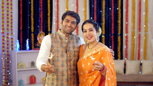 Diwali celebration with Diwali crackers  Indian couple burning sparklers during the Diwali festival. Husband and wife celebrating the festival at home  Diwali decoration  colorful festive backgroun... photo