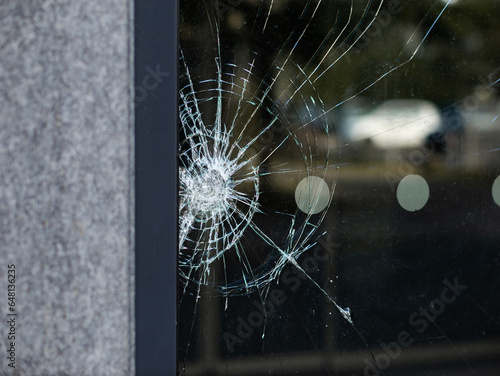 Broken security glass of a building exterior. The material is made of different layers to prevent splinters falling out. The thin and transparent plastic film inside holds the glass together.