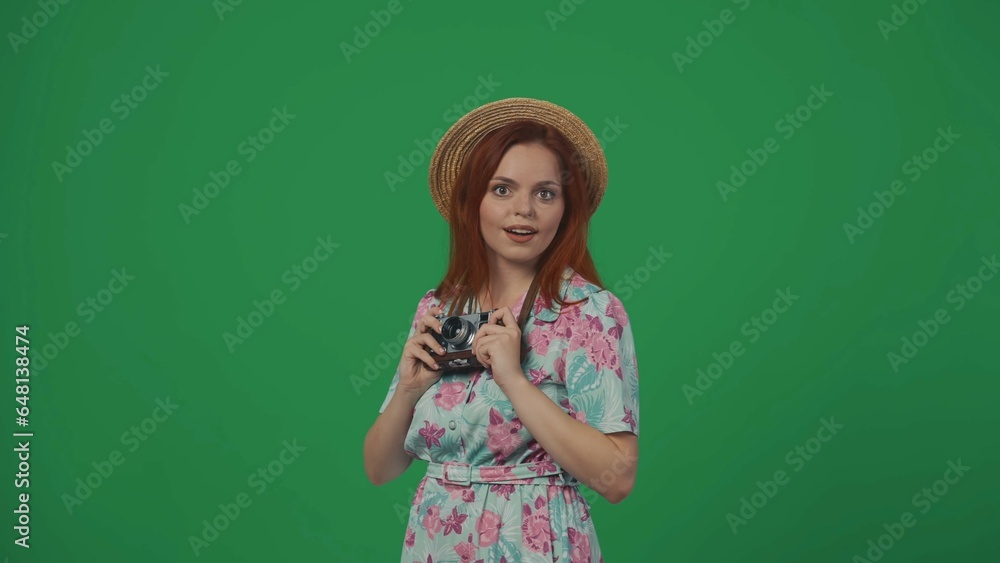 Woman traveller in straw hat holding old film cam looking at the camera ready to take photo, amazed face. Isolated on green background. Woman traveller in straw hat holding old film cam looking at the camera ready to take photo, amazed face. Isolated on green background.