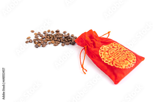 Coffee beans spilled from a red silk bag close-up with white background