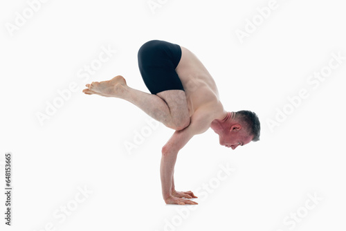 Bakasana ( Crane pose), Ashtanga yoga  Side view of man wearing sportswear doing Yoga exercise against white background.