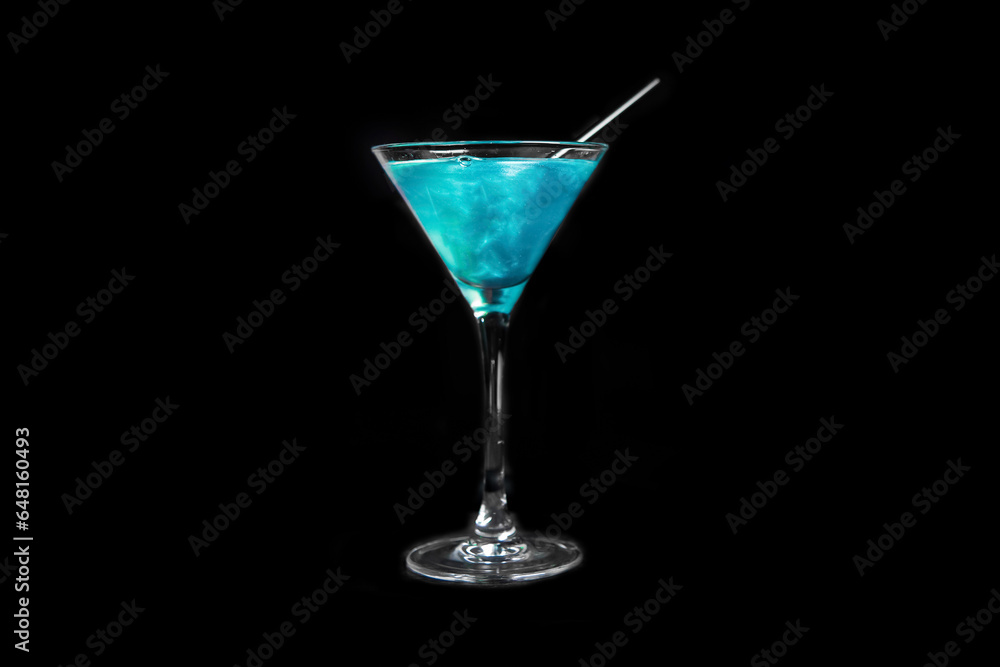 A martini glass with a blue alcoholic beverage and a straw on a black background