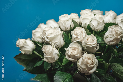 Bouquet of many white flowers, roses, close-up on a blue background
