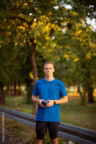 An athlete is resting, a man is standing with headphones, a blue T-shirt