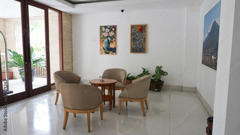 Fototapeta premium Minimalist interior design of living room with cream colored chairs and a landscape painting background