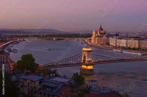 Picturesque aerial sunset cityscape view of Budapest. Illuminated Chain Bridge over Danube river and Parliament Building in the background. Travel and tourism concept