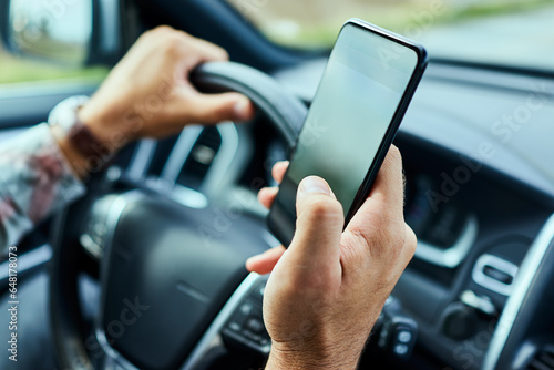 Young man using his smartphone to navigate himself while driving a car