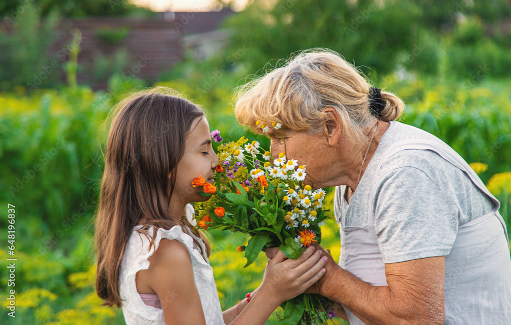 Grandmother and granddaughter hold medicinal herbs and flowers in their hands. Selective focus. Grandmother and granddaughter hold medicinal herbs and flowers in their hands. Selective focus.