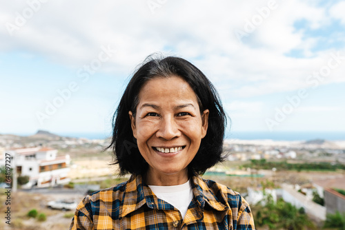 Happy Thai woman having fun having fun smiling into the camera at house rooftop