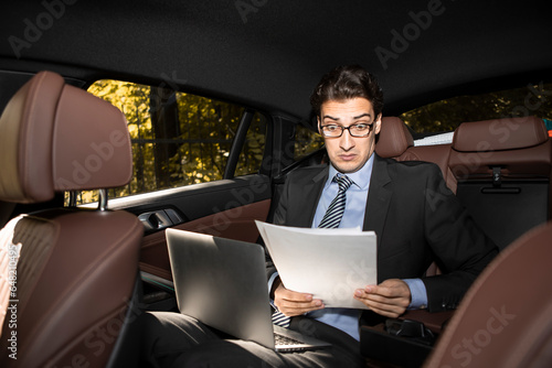 Depressed businessman sitting on backseat of his luxury car and feeling bad after overloaded work day in the office © Vitaliy