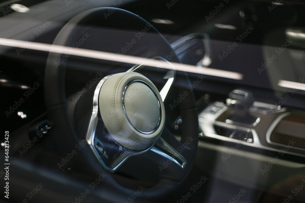 Expensive car interior view through glass with steering wheel, multimedia dashboard and gearbox handle