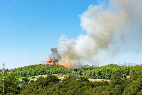 tragic view of forest fire and helibucket which  is a specialized bucket suspended on a cable carried by a helicopter to deliver water for aerial firefighting  photo