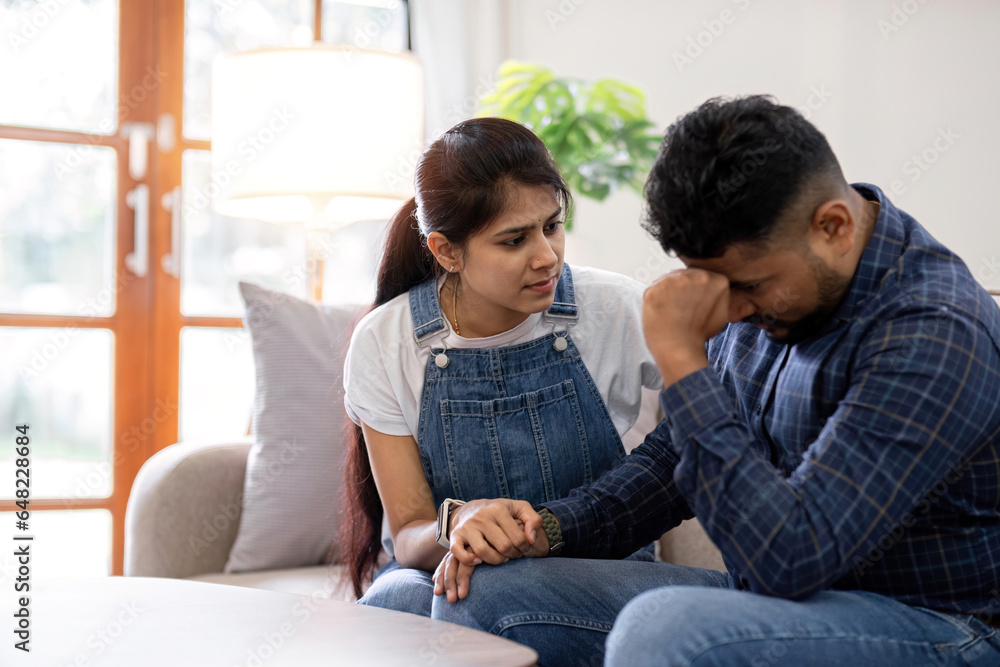 A young woman encourages and holds the hand of her worried husband. is having a hard time making some decisions. A young woman encourages and holds the hand of her worried husband. is having a hard time making some decisions.