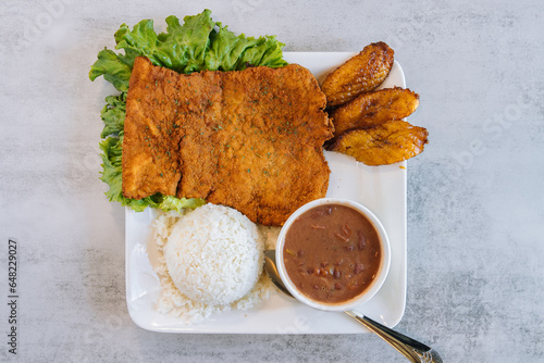 Deep fried pork Columbian dish with fried plantains rice and beans
