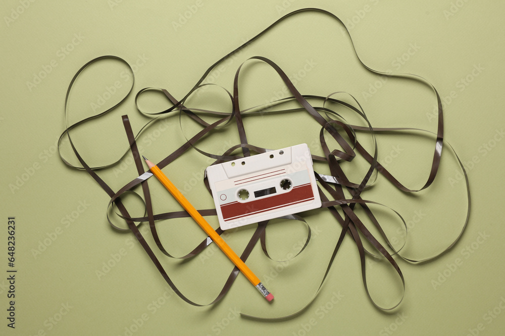 Audio cassettes with rolled up magnetic tape, pencil on green background Audio cassettes with rolled up magnetic tape, pencil on green background