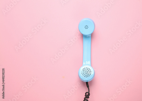 Retro blue telephone receiver on a pink background. Pastel color trend. Minimalism
