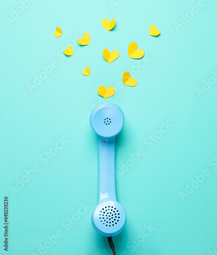 Retro blue telephone receiver with hearts on blue background. Top view. Minimalism