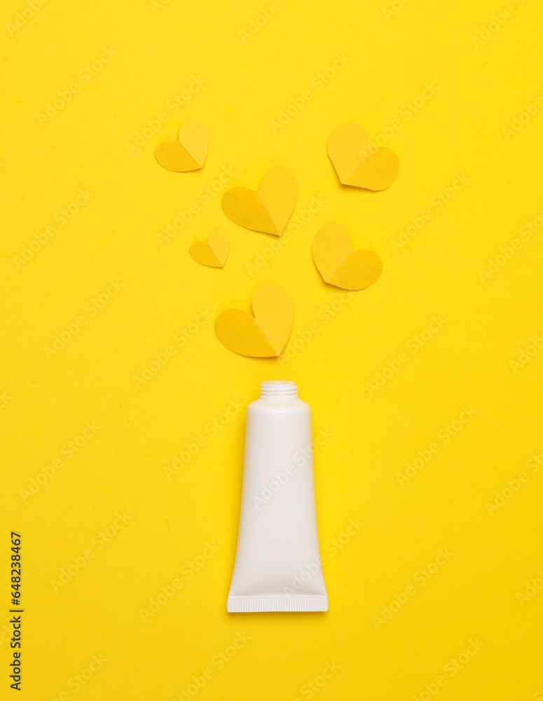 Tube of cream with hearts on a yellow background. Beauty, love concept Tube of cream with hearts on a yellow background. Beauty, love concept
