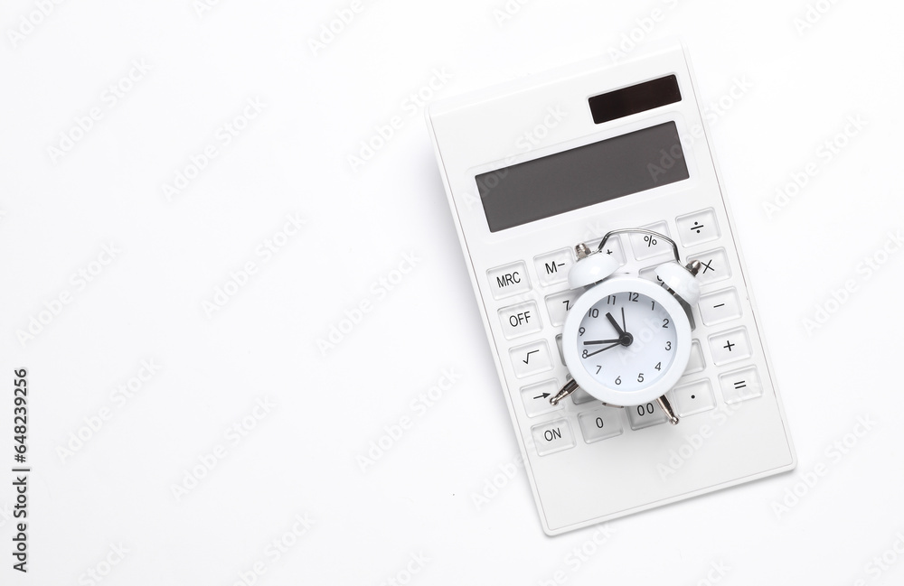Calculator with an alarm clock on a white background. Time is money. Business concept Calculator with an alarm clock on a white background. Time is money. Business concept