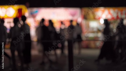 祭りの屋台と横切る人々のシルエット