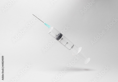 Syringe levitating on gray background with shadow. Nedicine concept photo