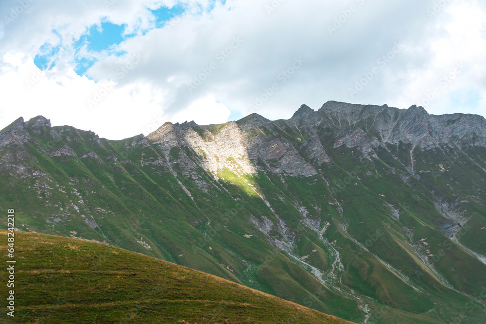The slopes of the Caucasus mountains are covered with forest and greenery.