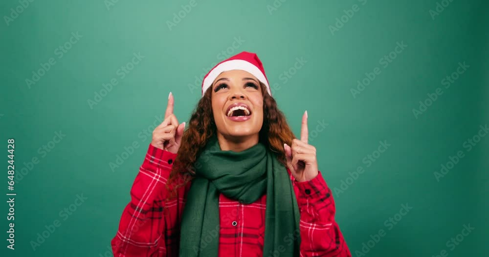 Excited young woman points up towards copy space, Christmas theme studio Excited young woman points up towards copy space, Christmas theme studio