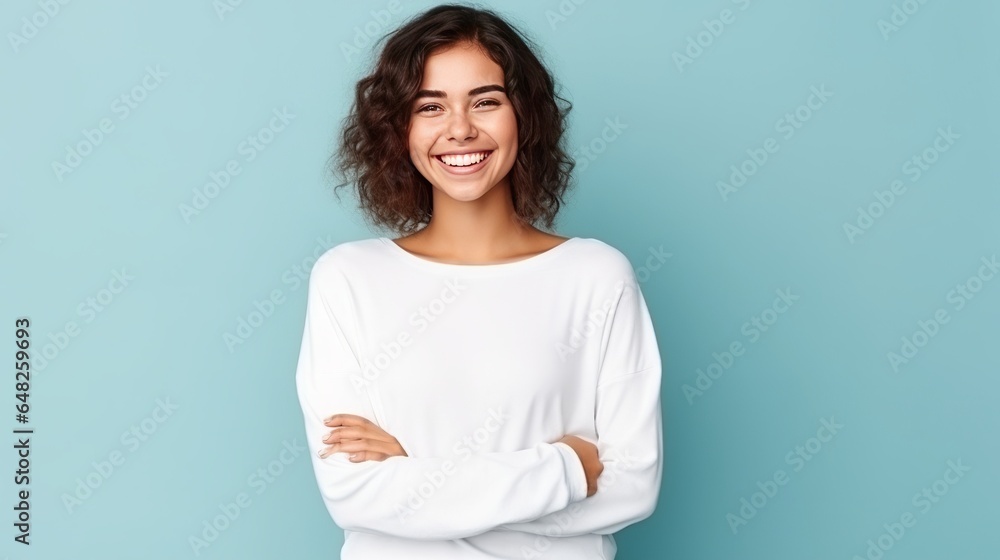 Young Caucasian woman smiling and posing with her arms at her hips on an isolated blue background. Young Caucasian woman smiling and posing with her arms at her hips on an isolated blue background.