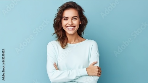 Young Caucasian woman smiling and posing with her arms at her hips on an isolated blue background. photo