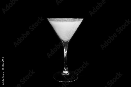A martini glass with a white alcoholic beverage on an black background