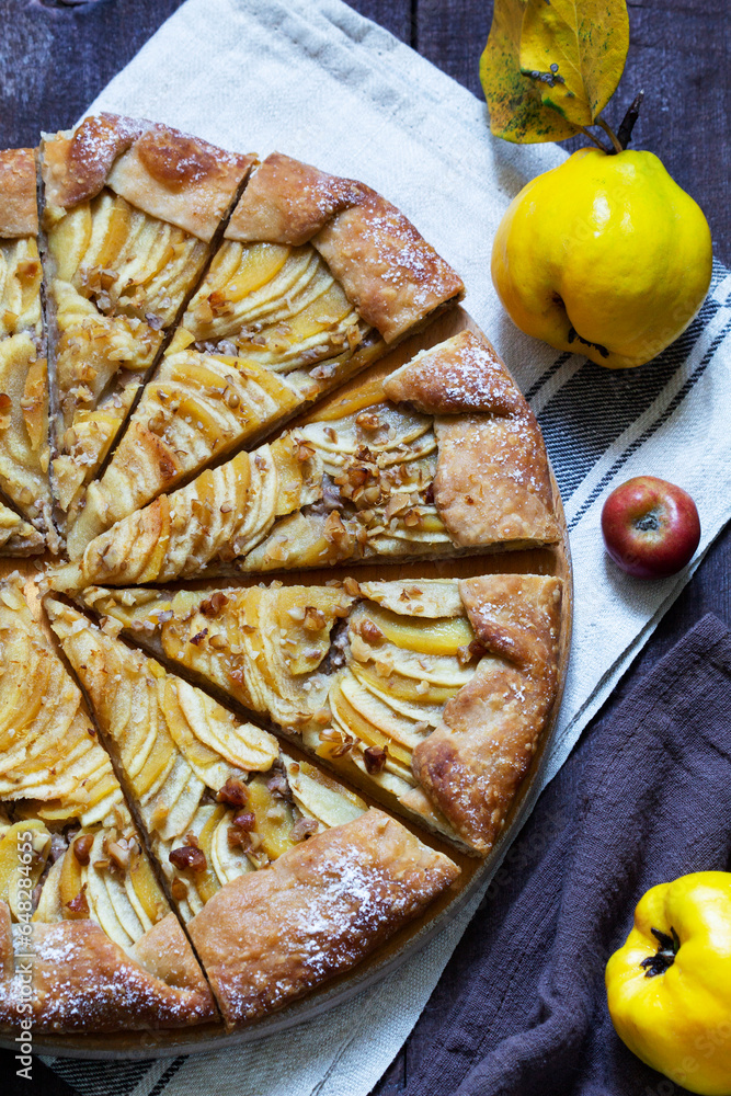 Open pie stuffed with apples, quince and nuts on a wooden background. Rustic style.